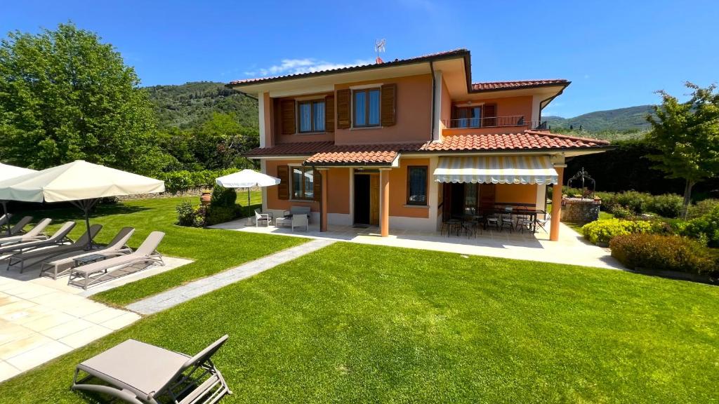 a view of a house with a lawn and chairs at Villino Blu 12 pax villa in Tuscany with private pool in Loro Ciuffenna