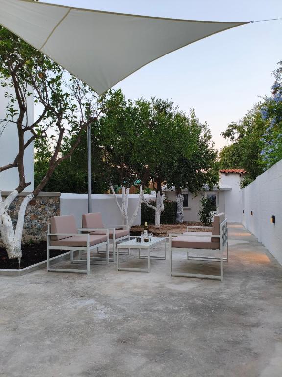 a group of chairs and tables under an umbrella at V House Cozy & Quiet Escape in Mytilene