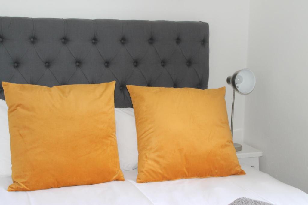deux oreillers orange sur un lit avec une tête de lit noire dans l'établissement @Oudam, à Montagu
