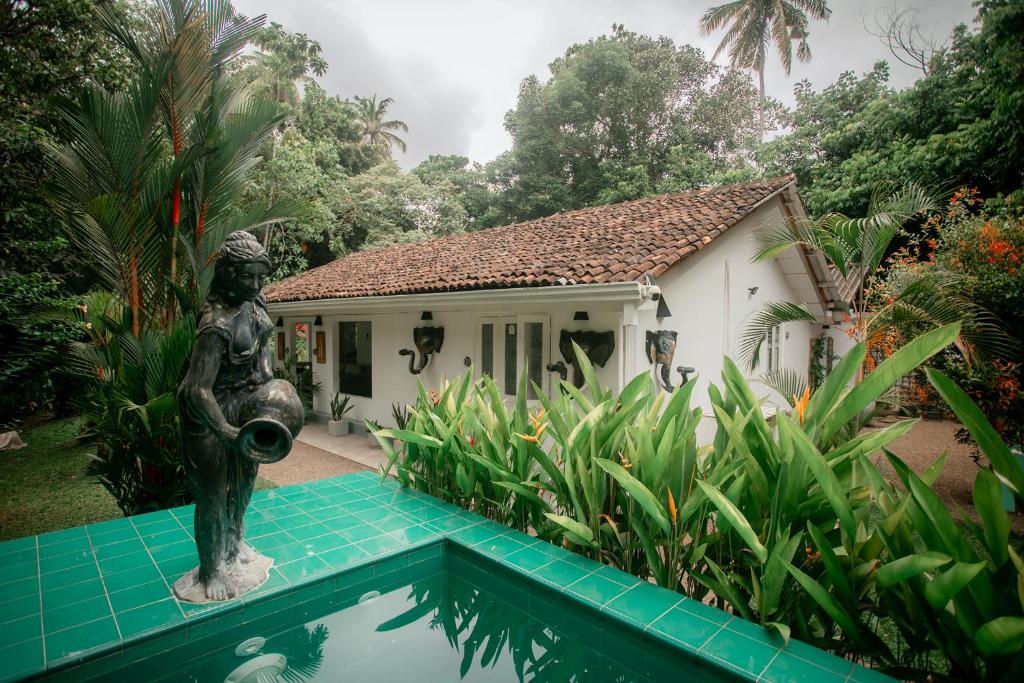 a statue in front of a house with a swimming pool at Jungle Villa Retreat in Galle