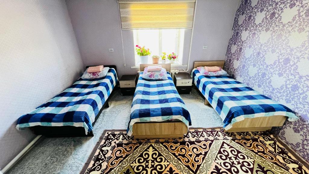 three beds in a room with a window at Mira Guest House in Kyzart