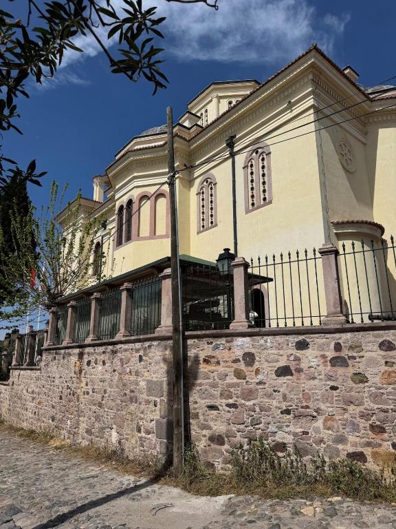 a large building on a stone wall with a fence at Melisa Garden in Cunda