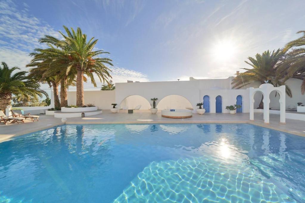 a large swimming pool with palm trees and a white building at Riad Salt Pool Bliss Apartamentos in Torremolinos