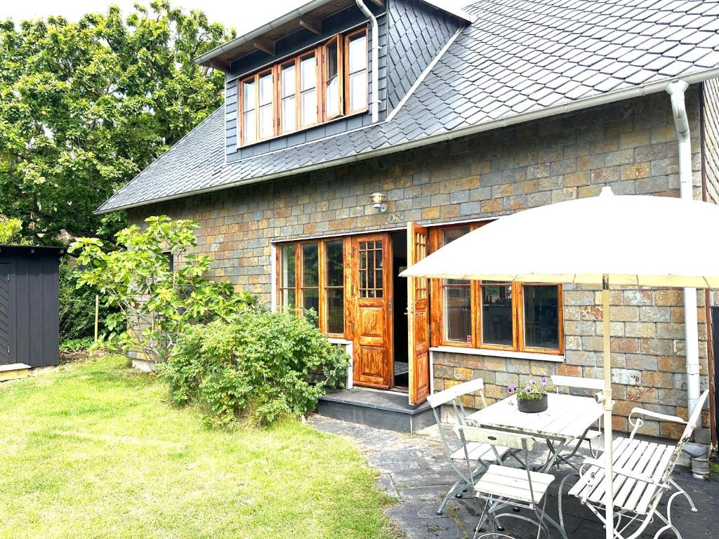 a house with a table and chairs and an umbrella at Genuint hus i Höganäs hamn in Höganäs