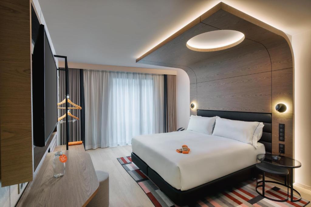 Cette chambre comprend un lit blanc et une télévision. dans l'établissement Canopy By Hilton Paris Eiffel Tower, à Paris