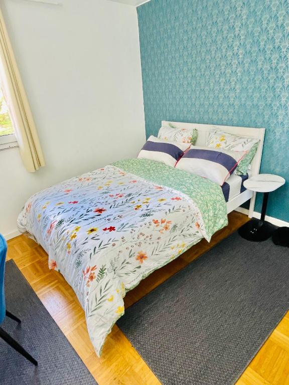 une chambre avec un lit avec un mur bleu dans l'établissement Chambre cosy proche de l'aeroport CDG, à Aulnay-sous-Bois