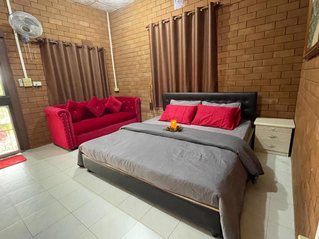 a bedroom with a bed and a red couch at บ้านมาดาม เขาใหญ่ in Ban Chek