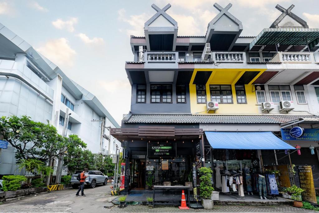 a building with a man walking in front of it at KAYAN Hostel in Chiang Mai