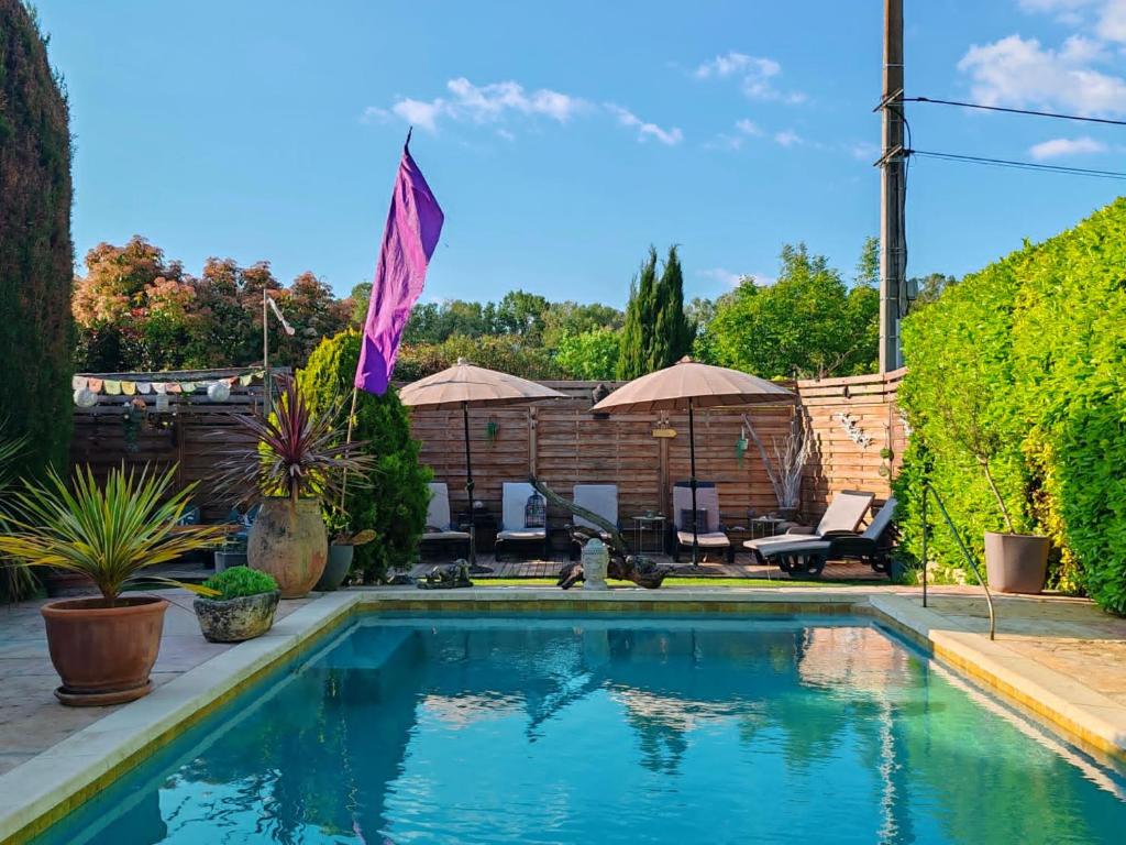 a swimming pool in a yard with chairs and umbrellas at le petit Mazet in Monteux