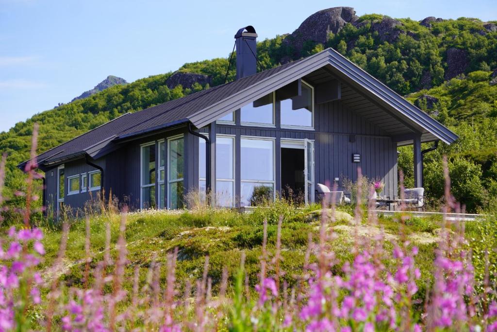 a house on a hill with a field of flowers at Sea Pearl Lodge in Leknes