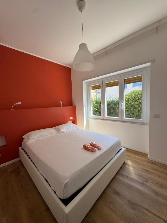 Un dormitorio con una cama blanca con una pared naranja. en Tiber Domus Fiumicino - Apt 2, en Fiumicino
