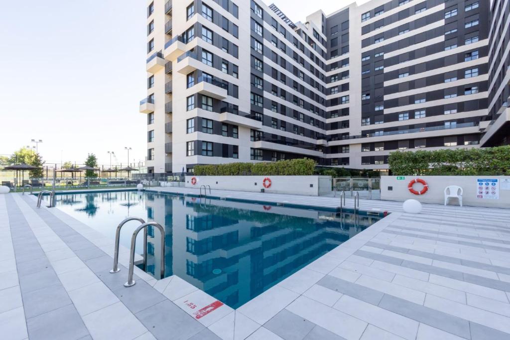 a swimming pool in front of some tall buildings at Be Casa - Valdebebas in Madrid