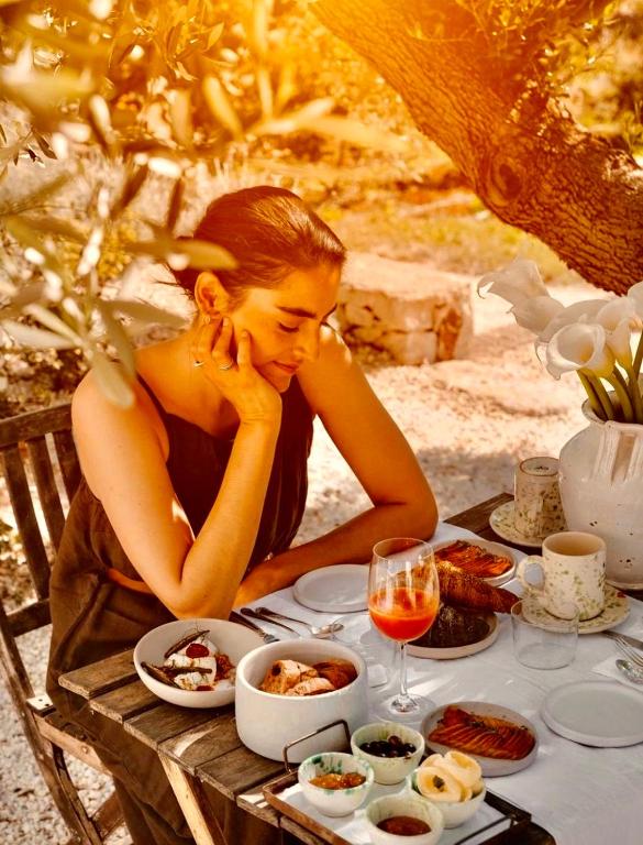 a woman sitting at a table with food and wine at Eman Resort & Villas in Ulcinj