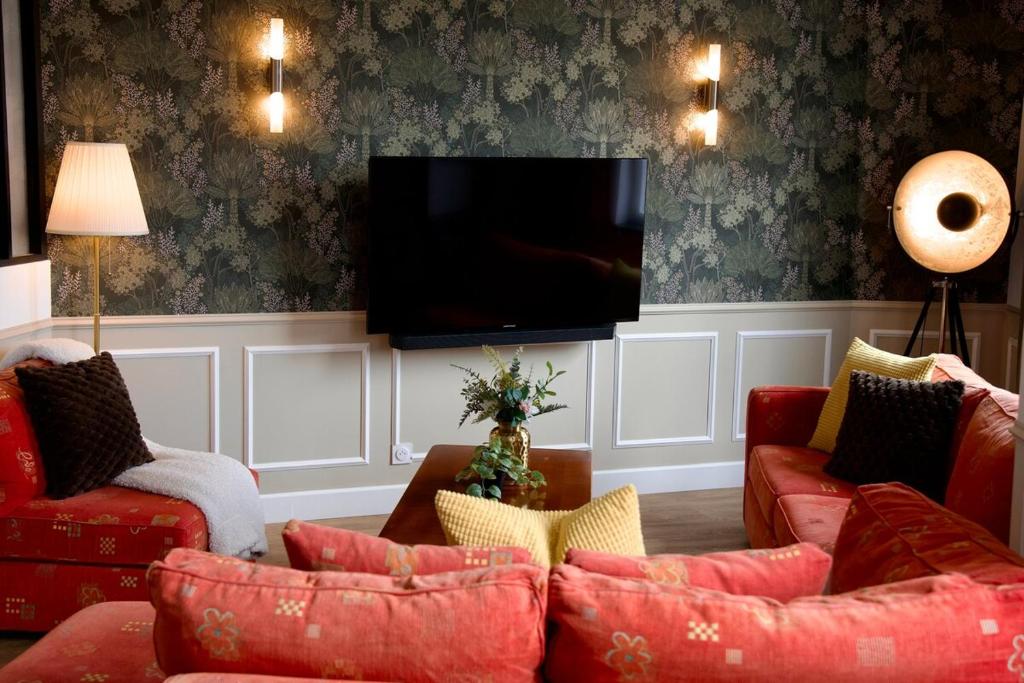 a living room with red couches and a flat screen tv at Le Familia in Guer