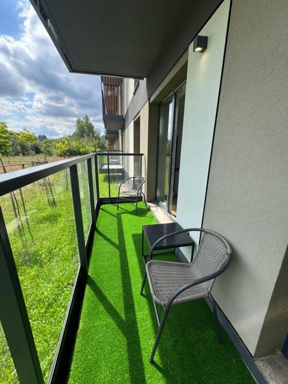 two chairs sitting on a balcony with green grass at Apartament Premium No 5 - Faktura VAT - Targi Kielce - Parking - Blisko Terenów Zielonych - NEW in Kielce