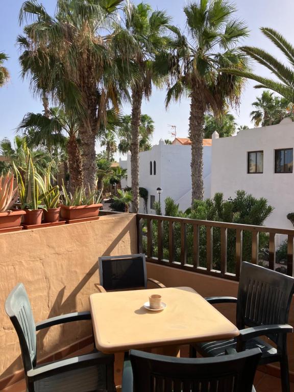 a table and chairs on a balcony with palm trees at Confortable Apartment in Corralejo in Corralejo