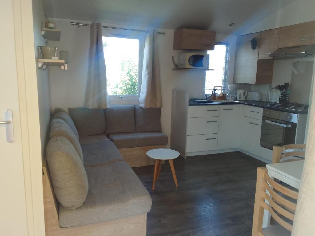 a living room with a couch and a kitchen at Camping le lac des rêves Mobil home "Séléna" possibilité location trottinette Electrique in Lattes
