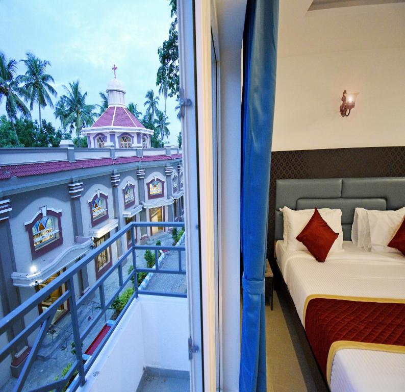 a room with a balcony with a view of a building at A K G Hotel in Puducherry