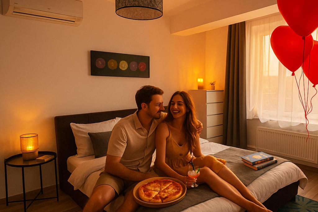 a man and woman sitting on a bed with a pizza at Vila luminoasa cu curte privată in Bucharest
