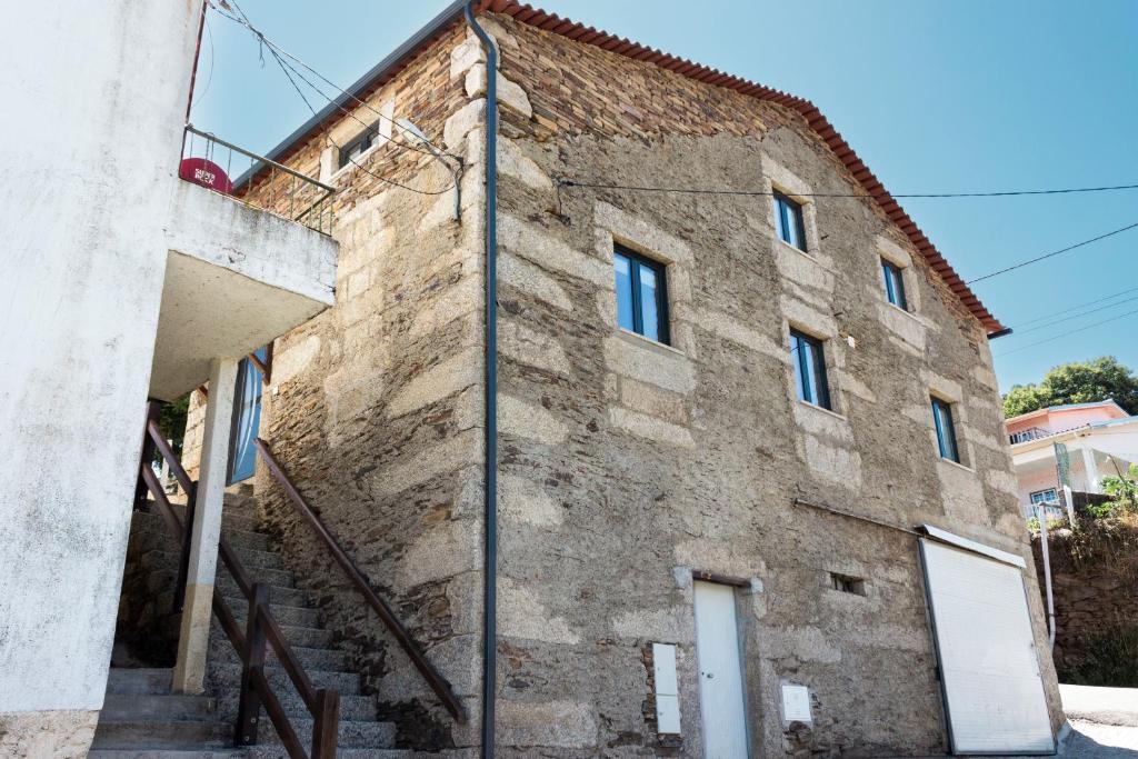 ein altes Steingebäude mit einer Treppe davor in der Unterkunft Casa da Ladeira in Videmonte