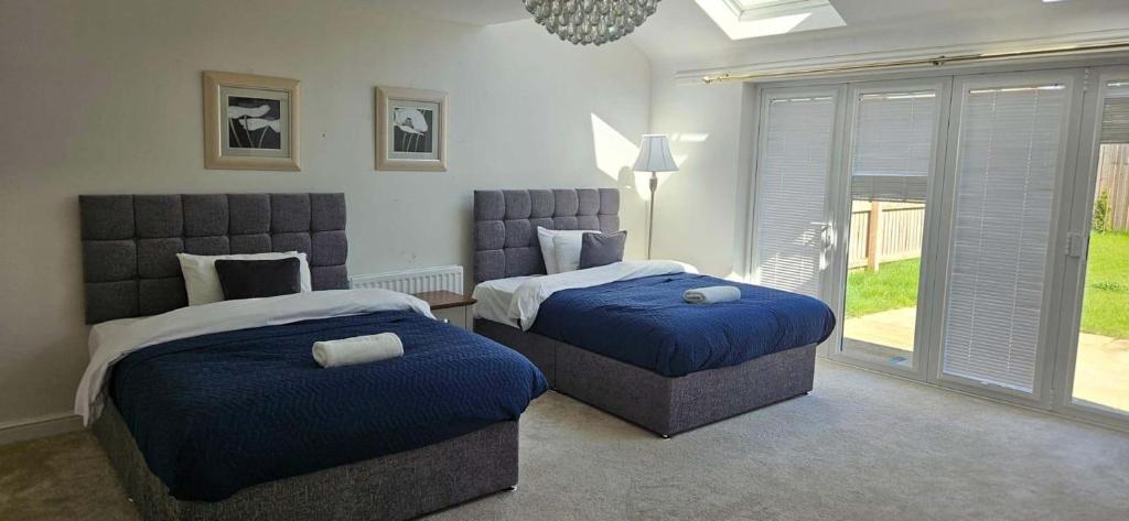 een slaapkamer met twee bedden met blauwe dekens en een raam bij Spacious Luxurious Serviced Accommodation 7 in Preston