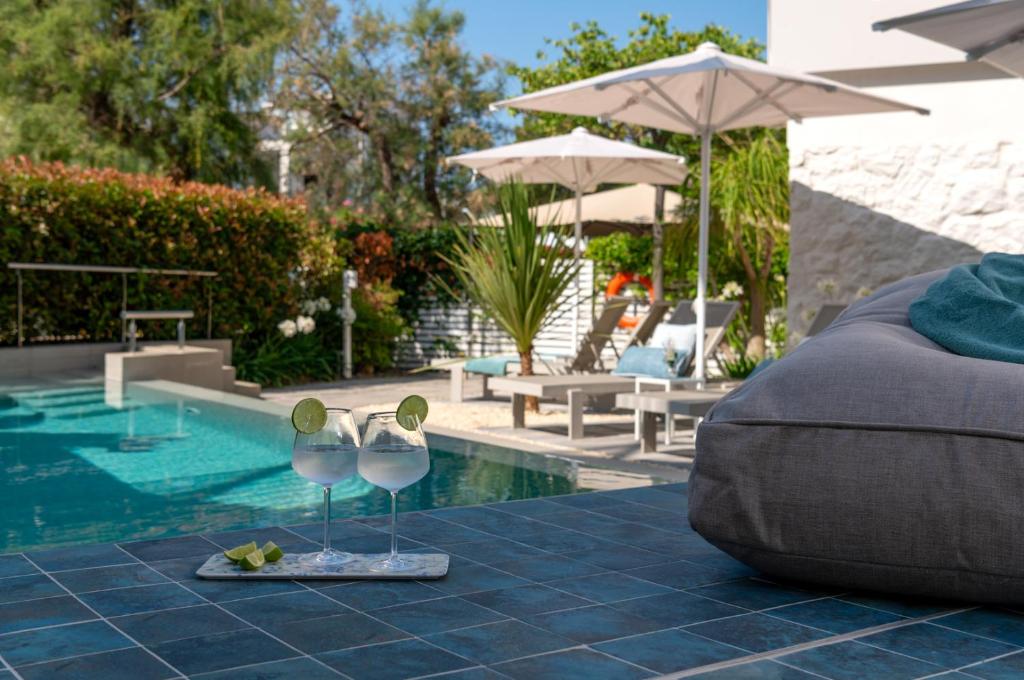 a pair of wine glasses sitting next to a swimming pool at 1935 Hotel Boutique & Apartments - Adults Only in Roses