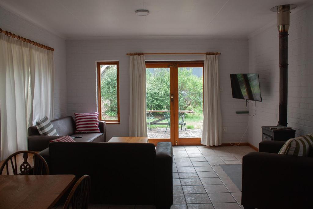a living room with a couch and a tv at Yellowwood Place in Bettyʼs Bay