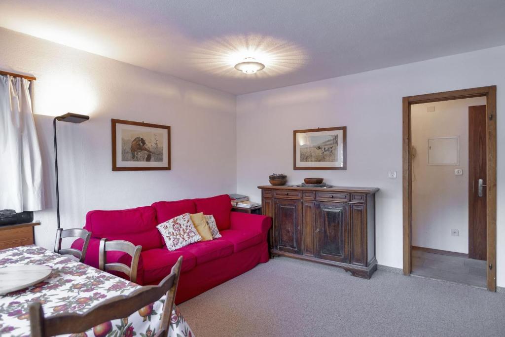 ein Wohnzimmer mit einem roten Sofa und einem Tisch in der Unterkunft Chesa San Gian first floor - Celerina in Celerina