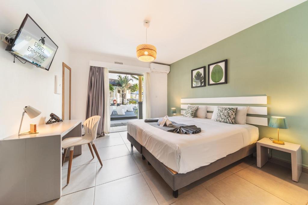 a bedroom with a bed and a desk and a computer at Hôtel Exsel Ermitage in Saint-Gilles-les-Bains
