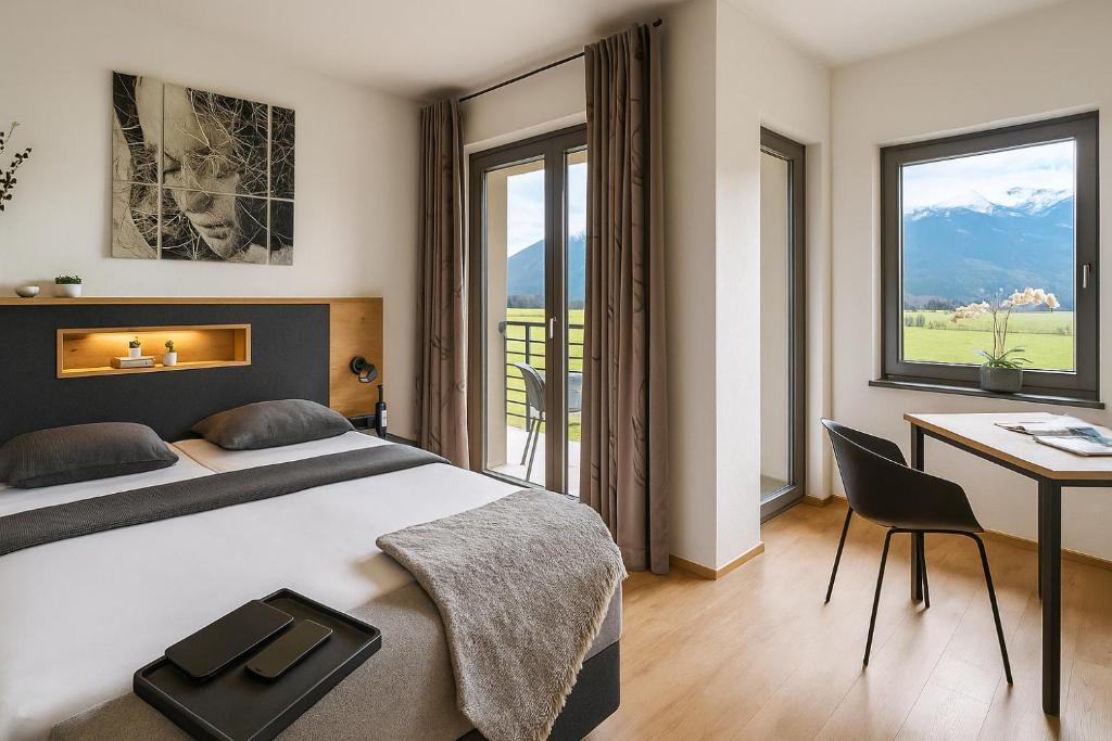 Una habitación de hotel con una cama, un escritorio y ventanas. en Sattler Living Apartments, en Ebbs