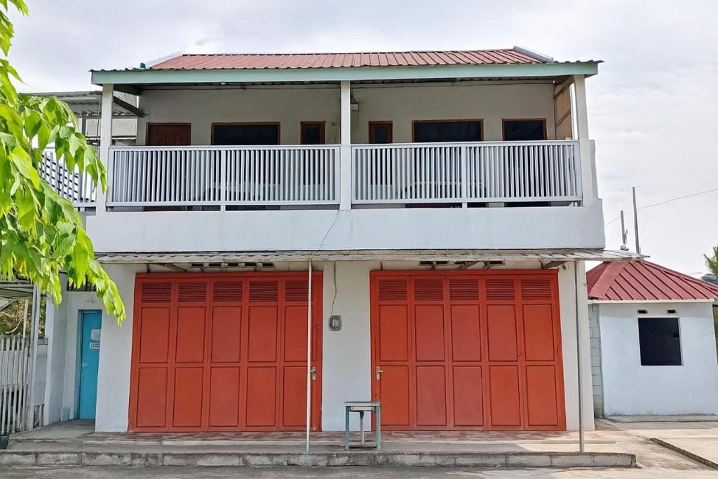 a house with red garage doors and a balcony at OYO 94717 Homestay Ka Villa Syariah in Boyolali