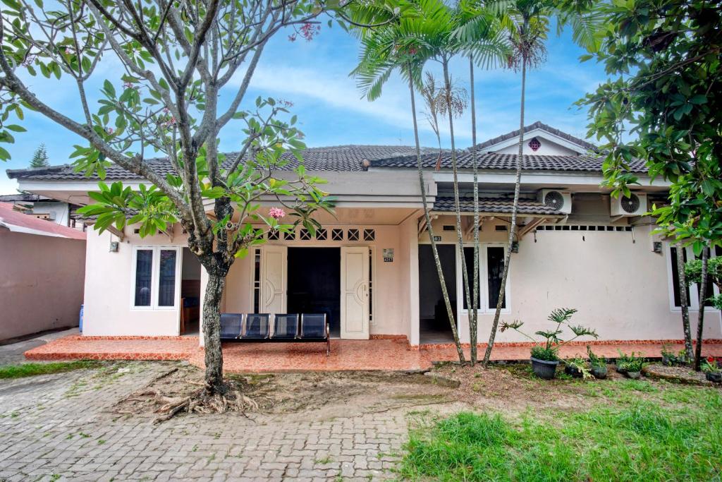 a white house with a tree in front of it at Hotel O Twin Kostel in Palembang
