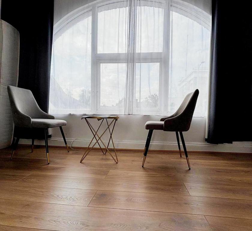 two chairs and a table in front of a large window at Cosy Flat Goodmayes in Goodmayes