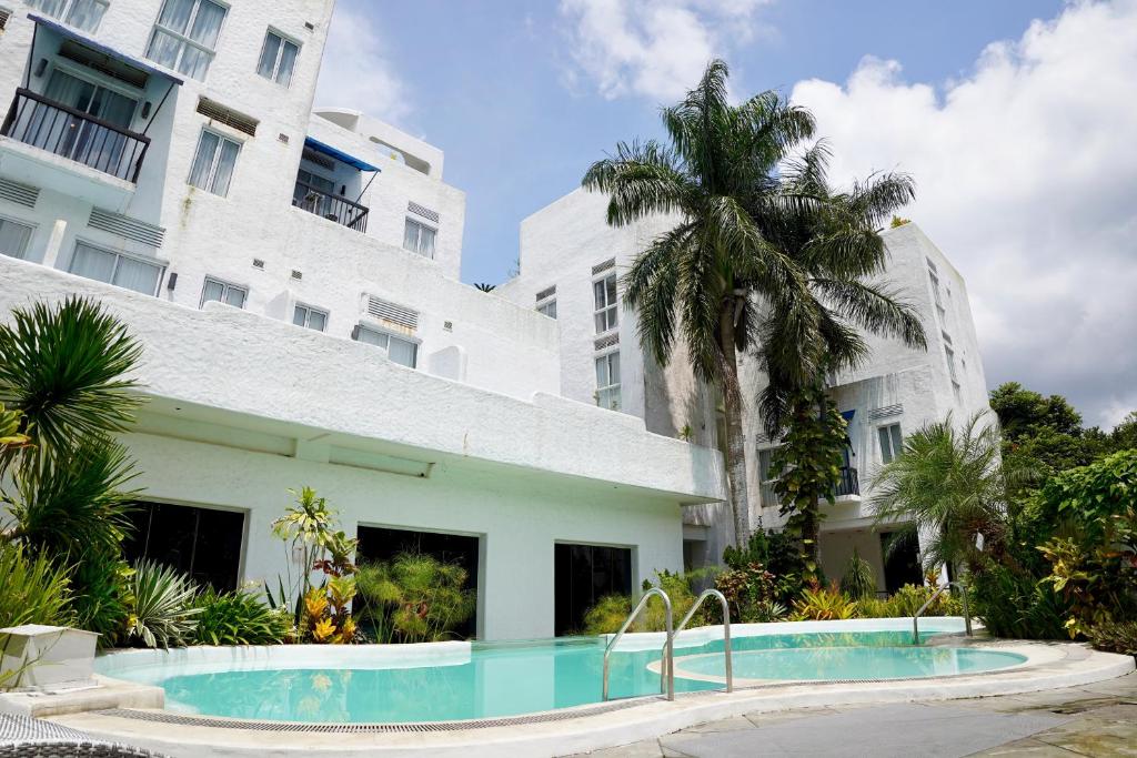 Santorini Lia Soleil at La Bella Tagaytay في Galicias: حمام سباحة أمام مبنى به شجرة نخيل