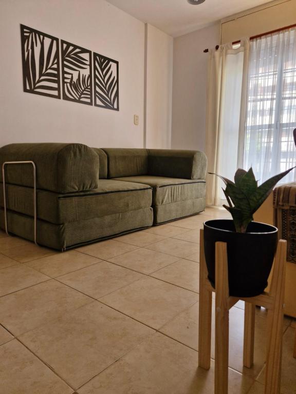 ein Wohnzimmer mit einer Couch und einer Topfpflanze in der Unterkunft Francia Apartment in Rosario