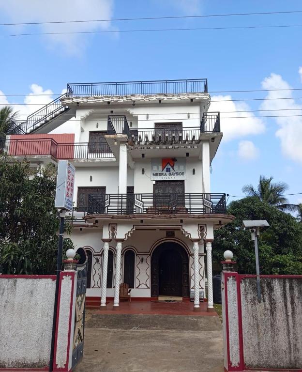 a white building with a balcony on top of it at Meera Bayside Villas in Oddaimavadi