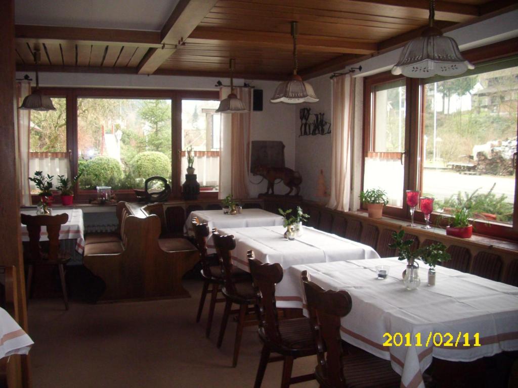 a dining room with tables and chairs and windows at Landhotel Pingel in Sundern