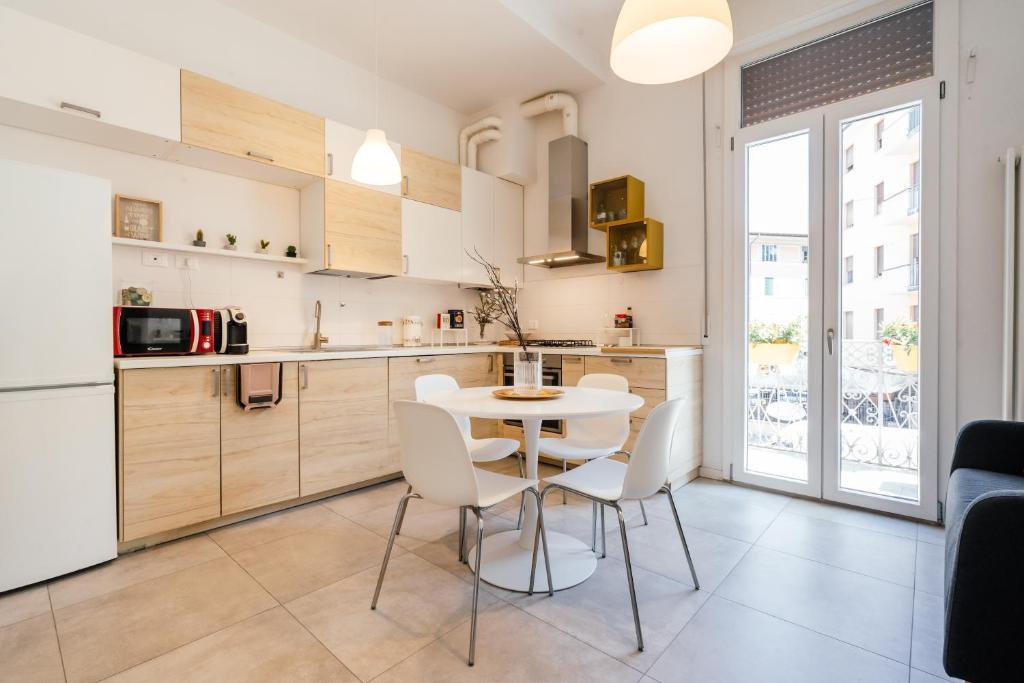 a kitchen with a white table and white chairs at Happy Home Spazioso Trilocale Bologna a Due Passi Dal Centro in Bologna