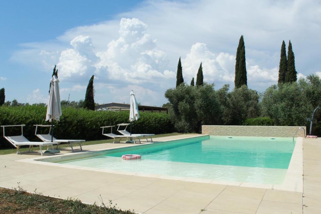 una piscina con dos sillas y sombrillas en Il Gelsomino Bio Agriturismo, en Alberese