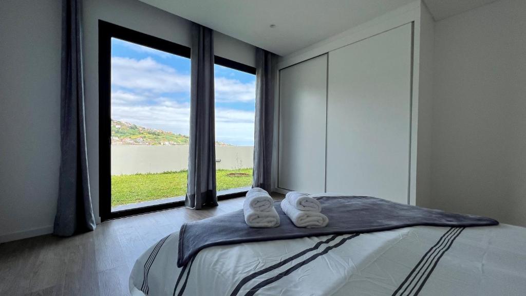 a bedroom with a bed and a large window at The Barreto's Clive in Ponta do Sol