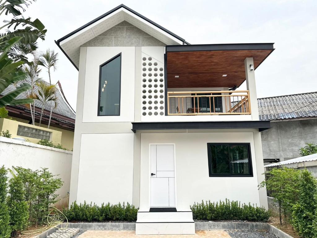 a white house with a balcony on top of it at Freeda House Bang Tao Beach - Near Muay Thai Gym in Ban Lum Fuang