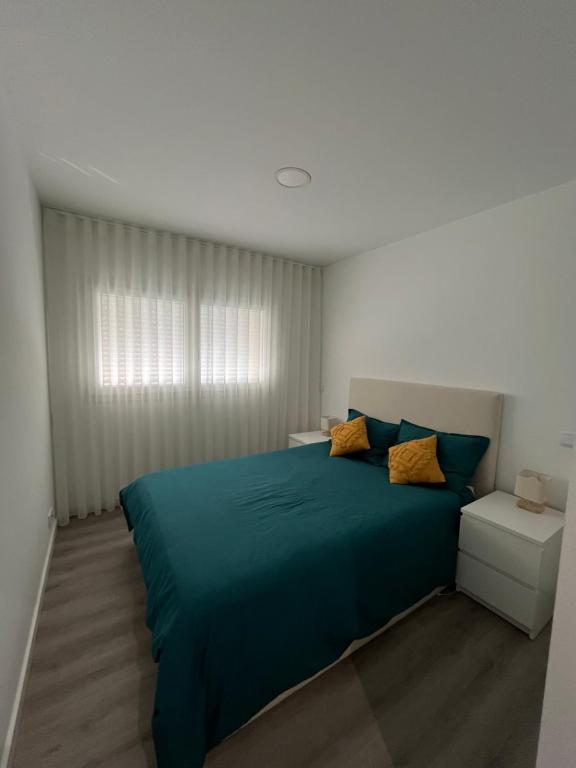 a bedroom with a blue bed and a window at Pombal Marquês Residence T2 in Pombal