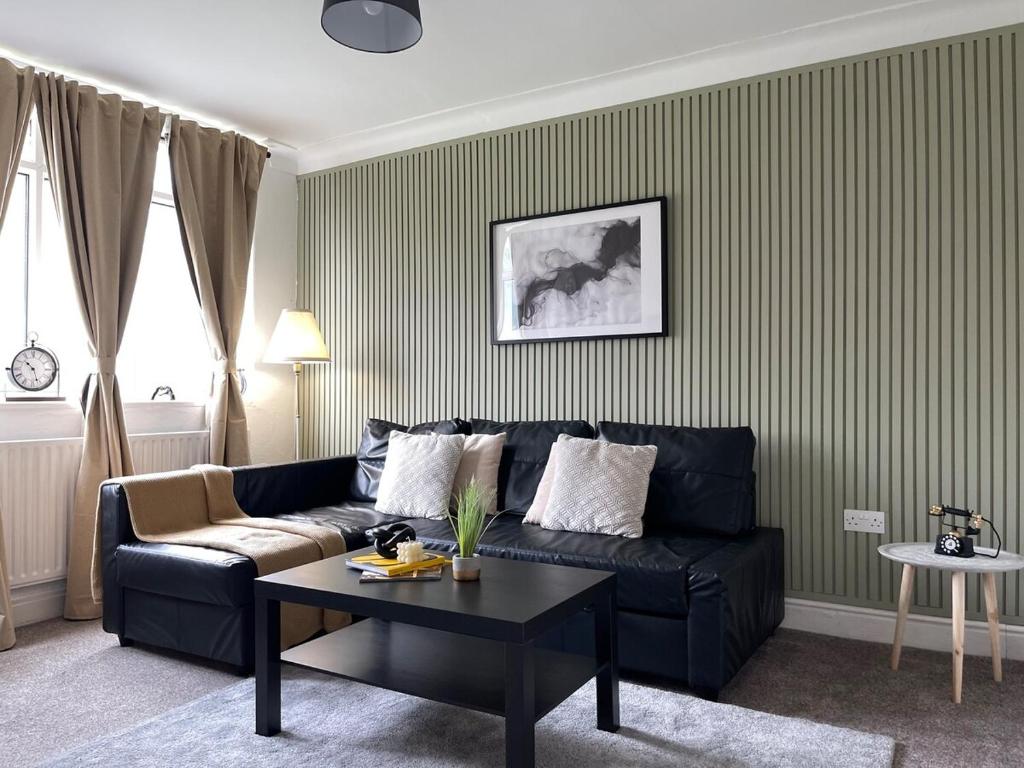 a living room with a black couch and a table at Spacious home in Woodhouse sleeps 9 guests! in Central Station
