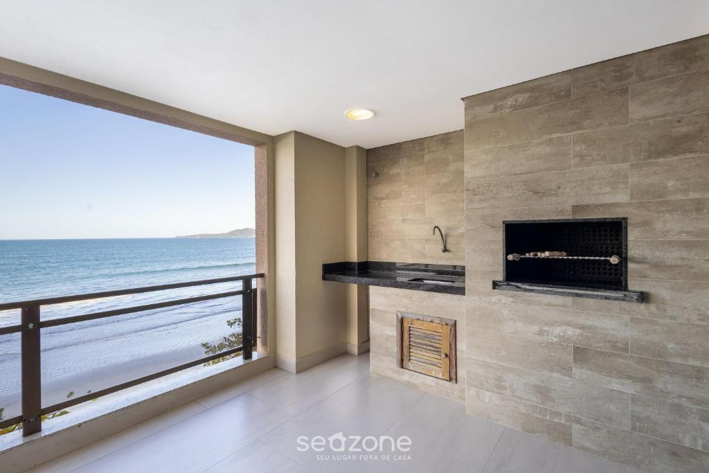 a room with a fireplace and a view of the ocean at Apto Beira-Mar c/ Vista p/ Praia VTE0301 in Meia Praia