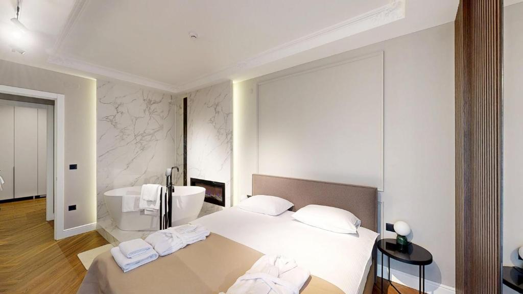 a white bedroom with a bed and a bath tub at Ideal Apartments in Banja Luka