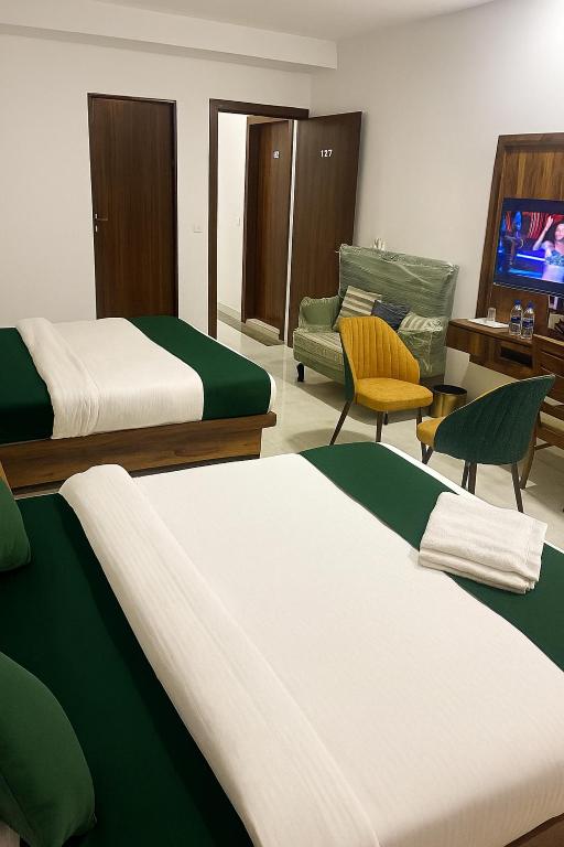 a room with two beds and a couch and a tv at Hotel Himanshi Executive in Mumbai