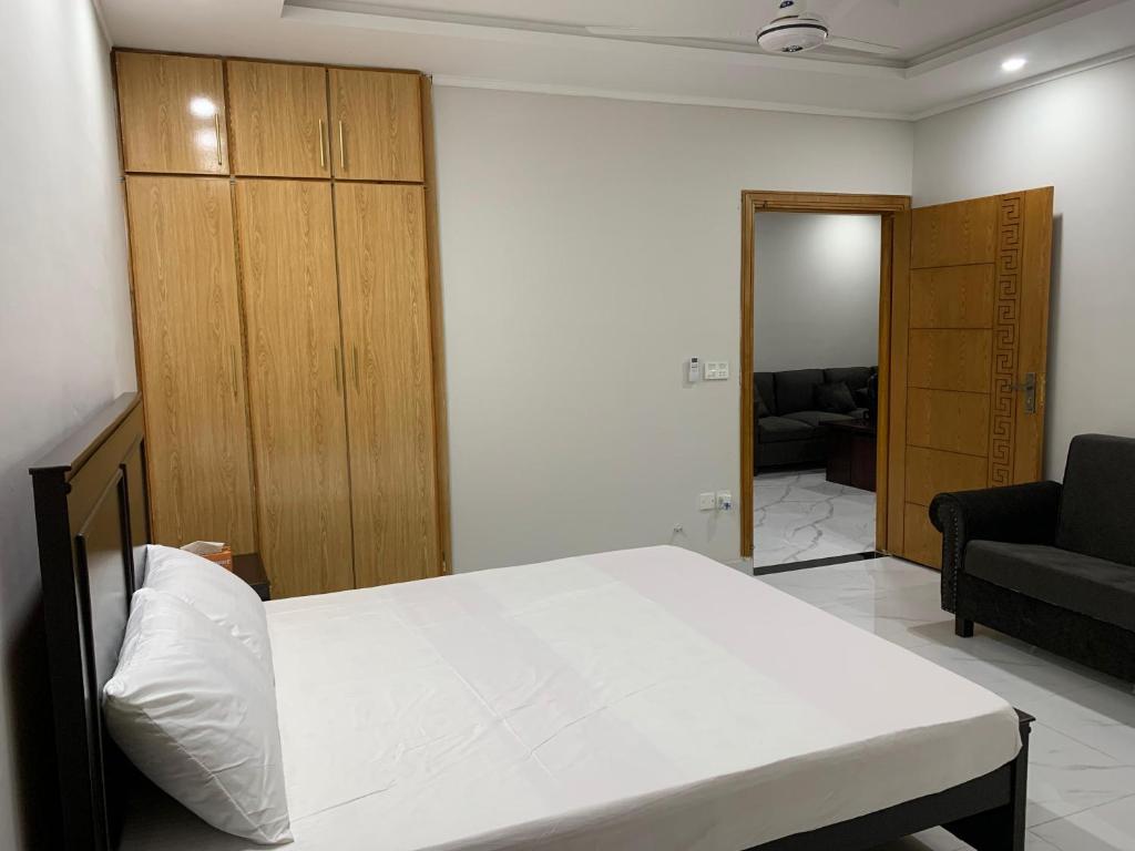 2-Bedroom Apartment near Islamabad International Airport Free Airport Pick and Drop في اسلام اباد: غرفة نوم بسرير ابيض واريكة