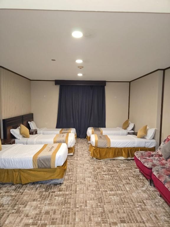 a hotel room with three beds and a couch at برج الجوار السكني أجياد المصافي Jiwar Tower Ajyad Al Masafi in Al Gharīth