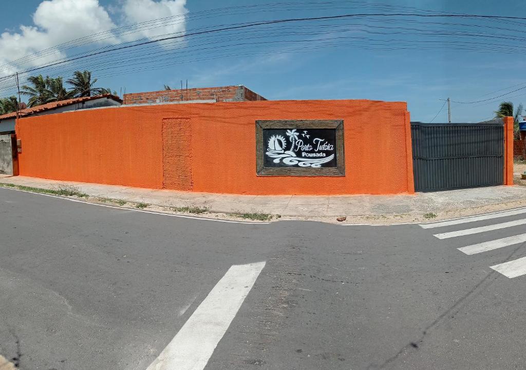 an orange wall with a sign on it next to a street at Pousada Porto Tutóia in Tutóia