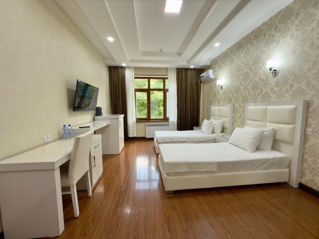 una camera d'albergo con 2 letti, scrivania di Wellmore Resort a Yusufkhona